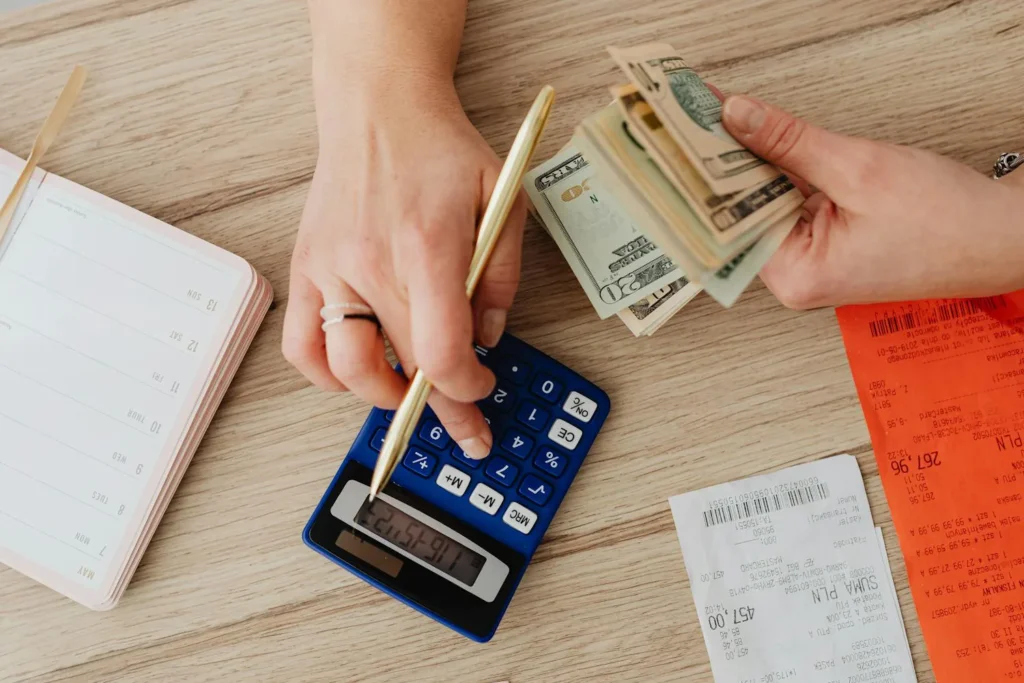 Person Using Calculator To Count Cash